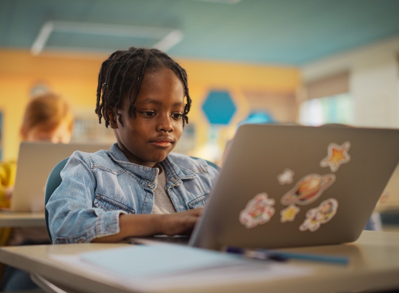 Young Boy Working On A Laptop At School